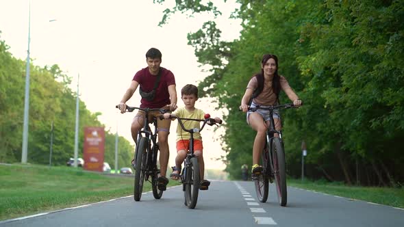 Family Biking on Road Near Forest