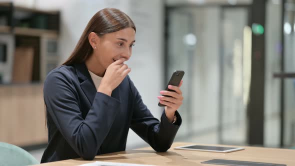 Excited Businesswoman Celebrating Success on Smartphone in Office 