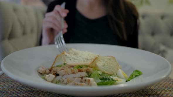 Female Eating Caesar Salad at Restaurant