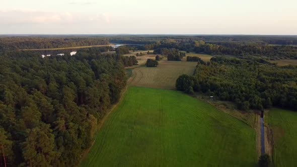 Spectacular aerial flight very high fly backwards drone shot lake and farm landin nature reserve Mü