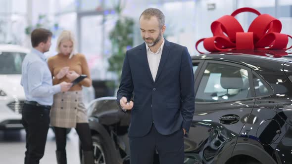 Happy Bearded Greyhaired Man Looking at Car Key and Gesturing Rejoicing Purchase of Luxurious