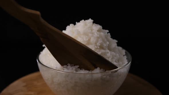 Cooked Rice in a Glass Bowl Rotates on a Black Background