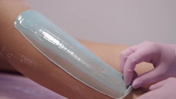Cosmetologist Placing Paste on Woman's Leg in Beauty Salon