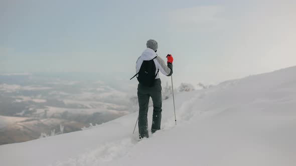 A Young Woman is Climbing a Snowcovered Mountain