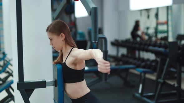 Strong Young Woman Performs an Exercise on the Simulator for Back and Triceps