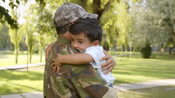 Happy Military Dad Holding Son in Arms Outdoors