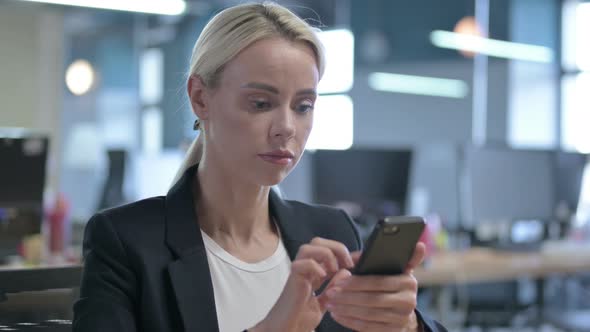 Young Businesswoman Using Smartphone at Work