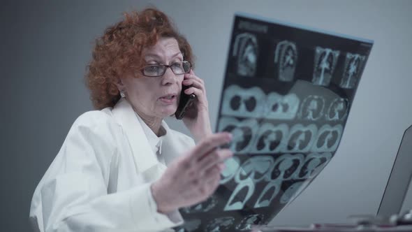 Happy Adult Woman Doctor Radiologist Discussing CT Scan of Patient's Lungs with Colleagues By Phone