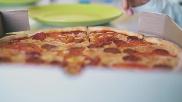 Boy Eats Tasty Pizza From Cardboard Box on Table Slow Motion