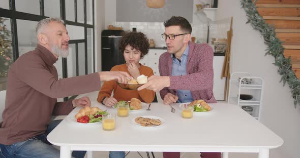 Gay Family Enjoys Breakfast Eating Fresh Bakery at Table