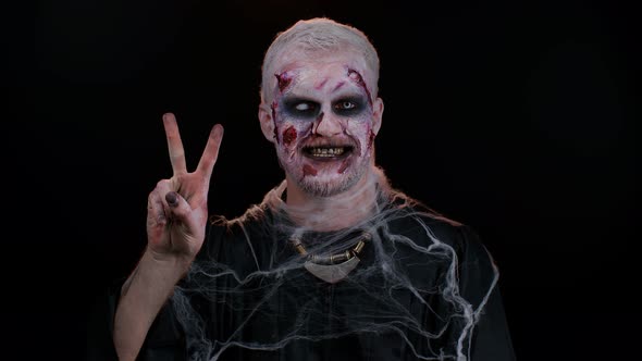 Halloween Zombie Man Bloody Makeup Showing Victory Sign Hoping for Success and Win Peace Gesture