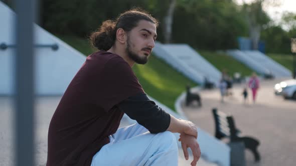 Portrait of Young Attractive Arab Man Sitting on the Stairs in Park at Sunset