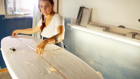 Woman making surfboard at workshop 