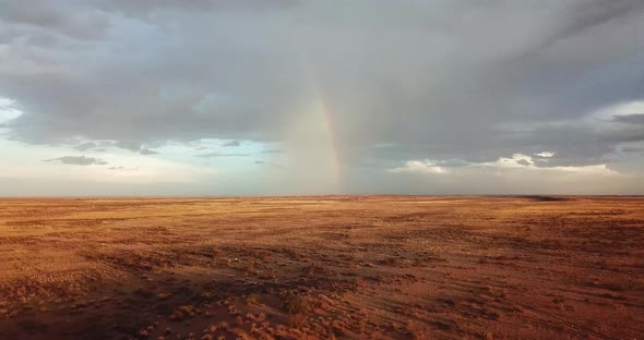 Drone shot of a rainbow in the distance on a very dry Namibian sheep farm. Drone moving forward with