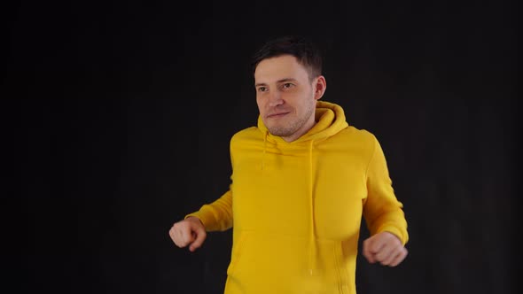 A Handsome Young Man Does Exercises Standing on a Black Background