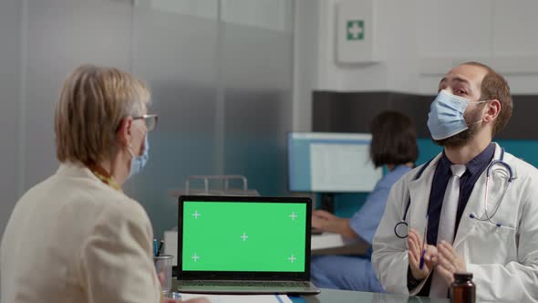 Retired Woman and Physician Analyzing Laptop with Greenscreen