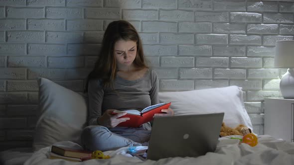 Young Mother Reading Books, Searching Baby Care Tips in Internet, Parenting