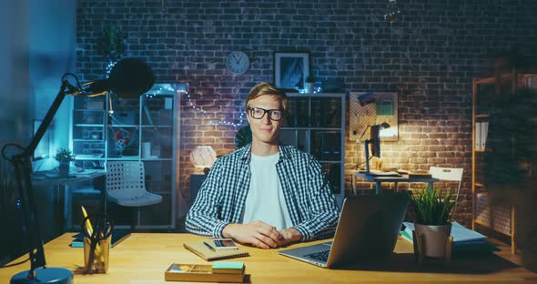 Zoom in Time Lapse of Handsome Man in Glasses Looking at Camera in Dark Office