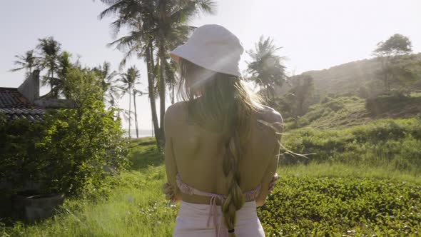 Blonde woman with braid and crossed arms near abandoned house on beach. Gimbal