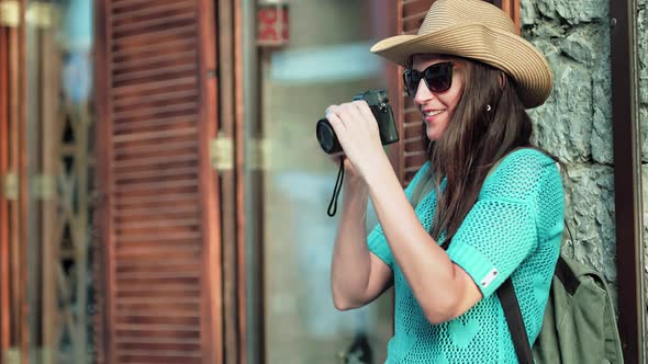 Young Female Tourist Photographer in Sunglasses and Hat Taking Photo Using Professional Camera