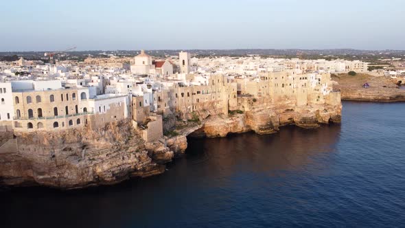 Aerial flying towards Polignano a Mare town at sunset. Italy