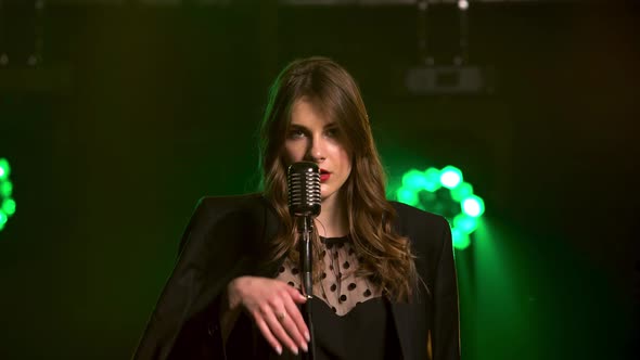 A Beautiful Girl Vocalist Sexually Moves Near on Stage in a Vintage Microphone. Stylish in a Black