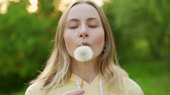 A Beautiful Young Woman Stands in the Forest and Blows a Dandelion, On the Street, Enjoy Nature