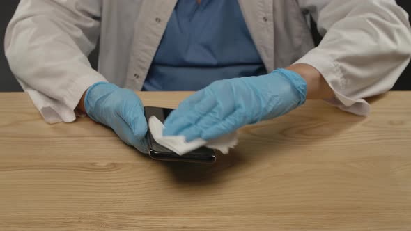 A Man Wearing Blue Gloves and a Protective Suit Uses a Damp Antibacterial Cloth To Remove Dirt