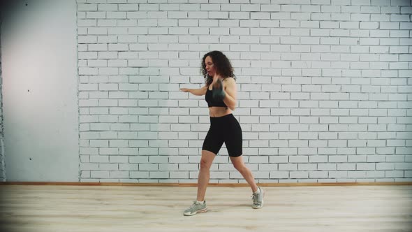 Workout in Sports Studio  Young Woman with Curly Hair Training Her Hands By Pulling the Weight