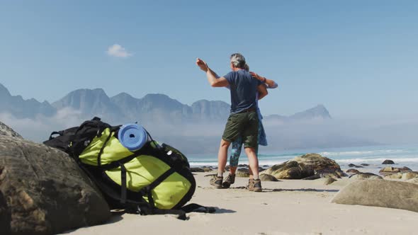 Senior hiker couple dancing on the beach while hiking.