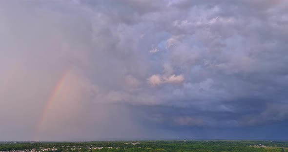 An Intense Thunderstorm Accompanied By a Bright Rainbow in the Sky During the Storm