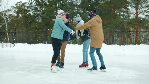 Slow Motion of Happy Men and Women Ice-skating Holding Hands in Winter Park