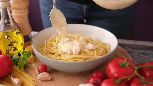 Making Pasta Carbonara  Adding Cream Sauce with Pancetta to Spaghetti in Ceramic Dish