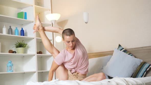 Confident Athletic Young Woman Sitting on Bed Doing Stretch After Workout at Home