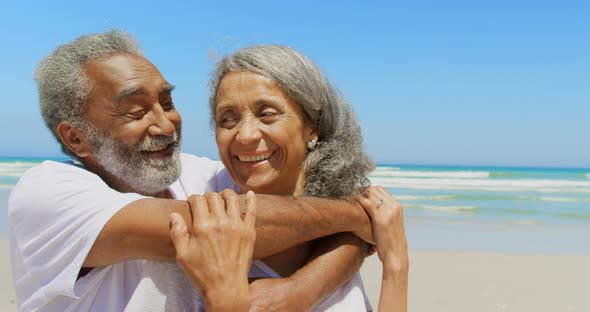 Front view of happy active senior African American man embracing senior woman on the beach 4k