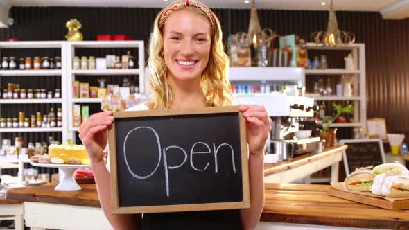 Smiling waitress showing chalkboard with open sign