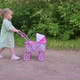 Little Girl Walking with Her Stroller Toy in Summer Park - VideoHive Item for Sale