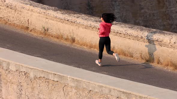 Asian woman jogging across the Salmon Falls Dam in Idaho