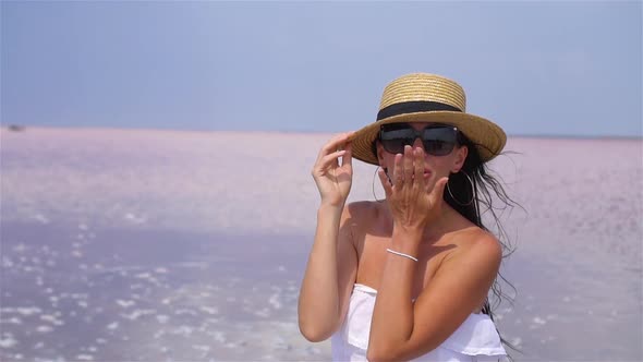 Woman in Hat Walk on a Pink Salt Lake on a Sunny Summer Day.