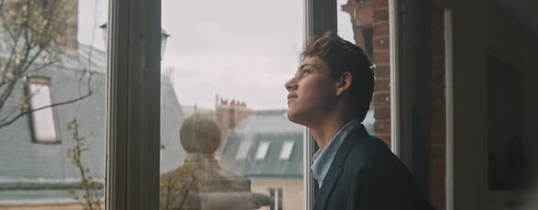 Young european man looking out of the window, daydreaming