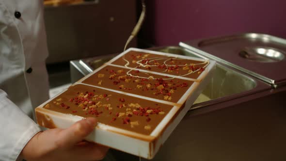 Worker drizzling white chocolate on chocolate mould