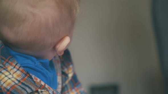 Cute Baby in Bright Clothes Plays with Spoon on Soft Bed