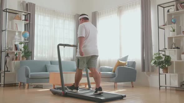 Back View Of Asian Fat Man Training On Walking Treadmill At Home