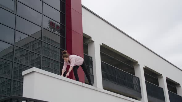 Young Female Gymnast Performs Handstand on Area Near Modern Buildings