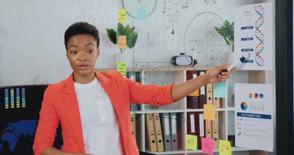 African american business lady talking and pointing at glass board and showing company growth