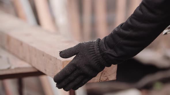 Close-up View in Slow Motion of Unidentified Worker in Working Gloves, Hand-stroking Sawn Place of