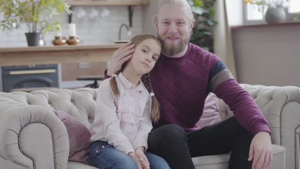 Portrait of Happy Caucasian Father Caressing Daughter's Head, Looking at Camera and Smiling. Young