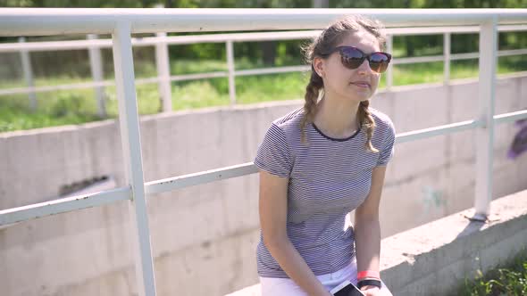 Portrait of an Attractive Smiling Caucasian Woman in a Park with Glasses