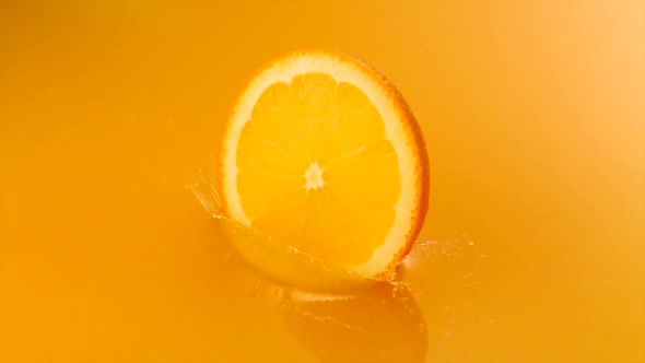 Sliced orange falling into orange juice, Slow Motion