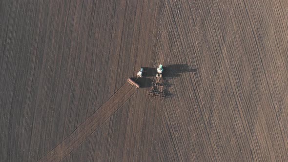 Aerial View of Tractor with Mounted Seeder Performing Direct Seeding of Crops on Plowed Agricultural